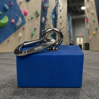 Grip strength blue pinch block in front of indoor rock climbing wall. 